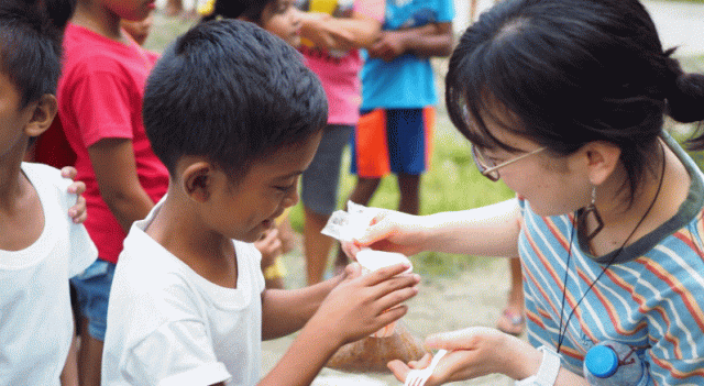 フィリピンの子どもたちにおやつを配る大学生